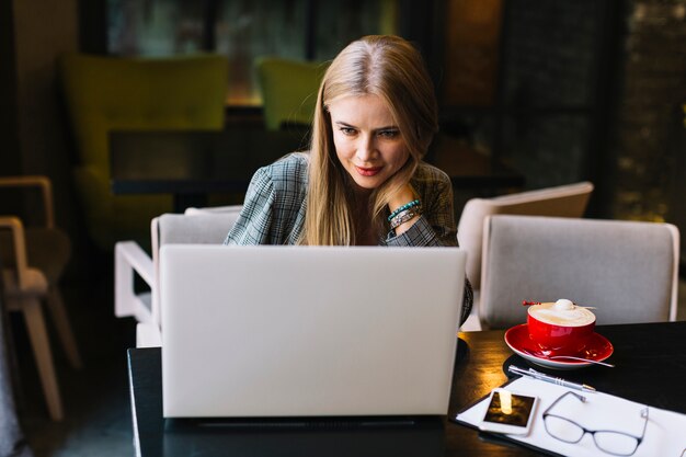 Mujer de negocios de estilo con portátil en cafetería agradable