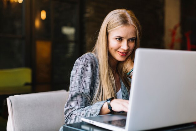 Mujer de negocios de estilo con portátil en cafetería agradable