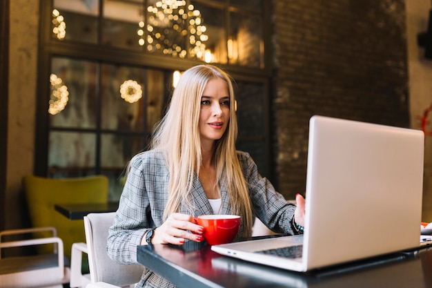 Mujer de negocios de estilo con portátil en cafetería agradable