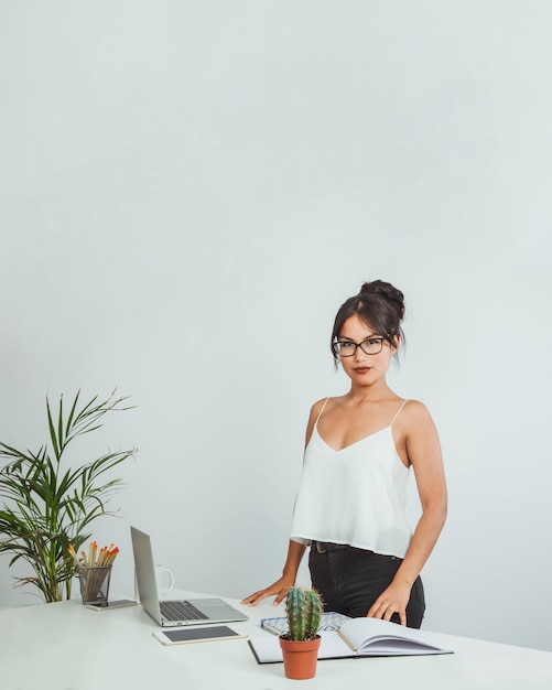 Mujer de negocios con estilo posando enfrente de su escritorio