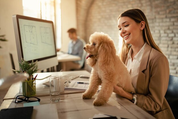 Mujer de negocios feliz disfrutando con su perro mientras trabaja en la oficina