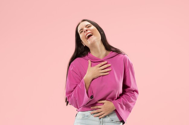 Mujer de negocios feliz de pie y sonriendo aislado en estudio rosa.