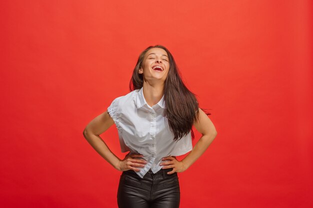 Mujer de negocios feliz de pie y sonriendo aislado en rojo. Hermoso retrato femenino de medio cuerpo.