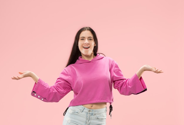 Mujer de negocios feliz de pie y sonriendo aislado sobre fondo rosa studio. Hermoso retrato femenino de medio cuerpo.