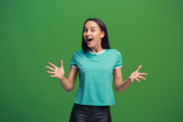 Mujer de negocios feliz de pie y sonriendo aislado sobre fondo verde de estudio. Hermoso retrato femenino de medio cuerpo. Joven mujer emocional.