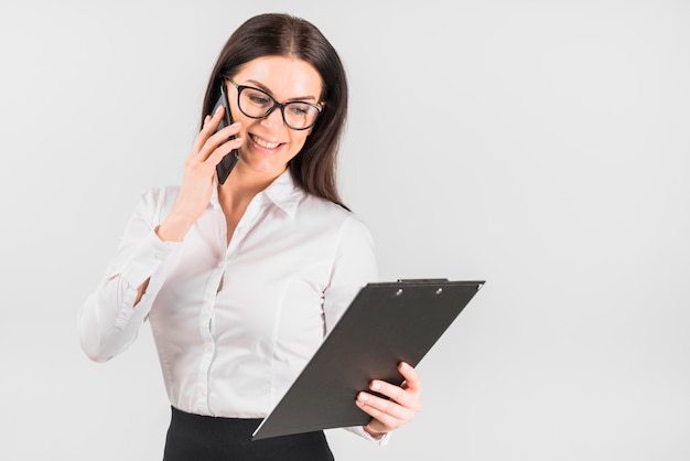 Mujer de negocios feliz con portapapeles hablando por teléfono