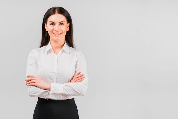 Mujer de negocios feliz que se coloca con los brazos cruzados