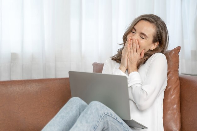 Mujer de negocios femenina usando una computadora portátil sentada en un sofá en casa