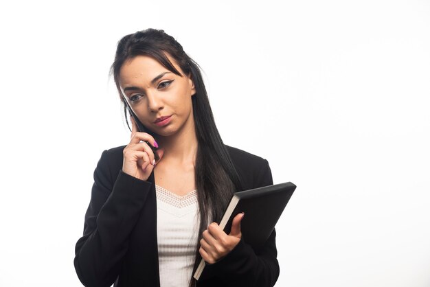 Mujer de negocios hablando por teléfono celular en la pared blanca