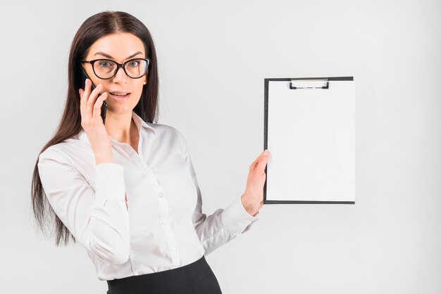 Mujer de negocios hablando por teléfono mostrando portapapeles