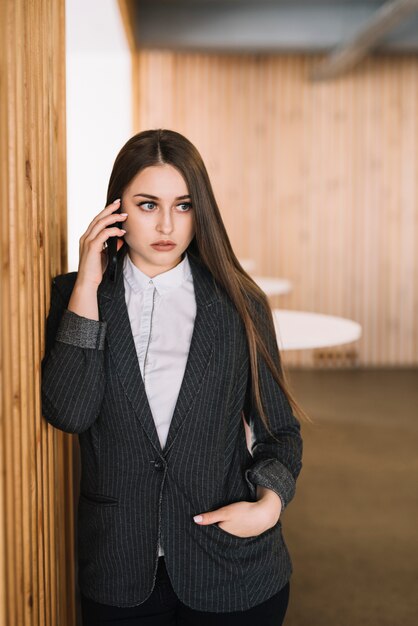 Mujer de negocios hablando por teléfono en la pared