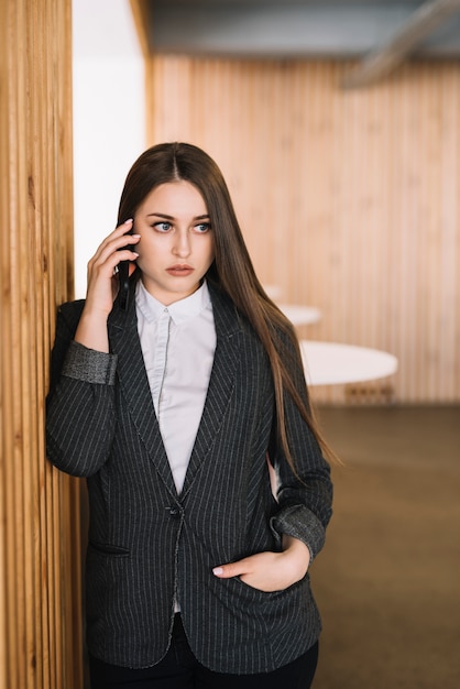 Mujer de negocios hablando por teléfono en la pared