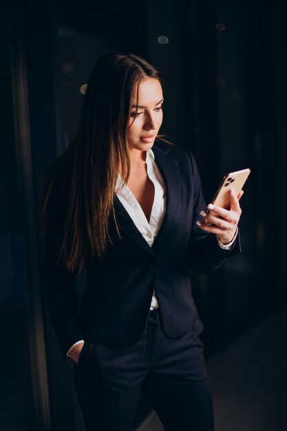 Mujer de negocios hablando por teléfono y quedarse hasta altas horas de la noche en la oficina