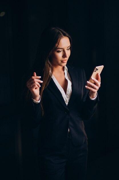 Mujer de negocios hablando por teléfono y quedarse hasta altas horas de la noche en la oficina