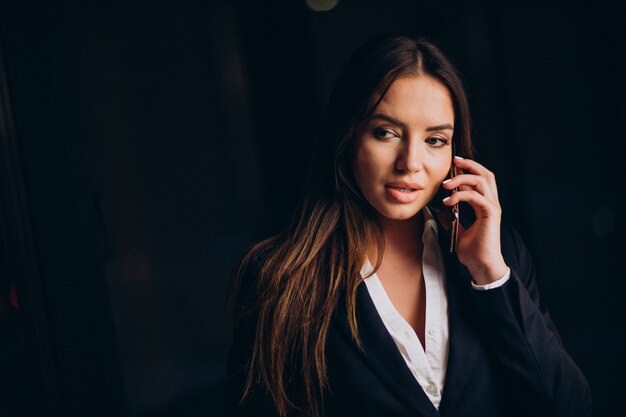 Mujer de negocios hablando por teléfono y quedarse hasta altas horas de la noche en la oficina