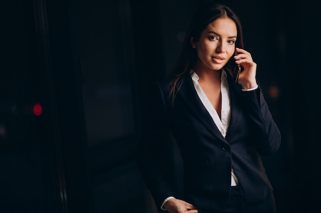 Mujer de negocios hablando por teléfono y quedarse hasta altas horas de la noche en la oficina