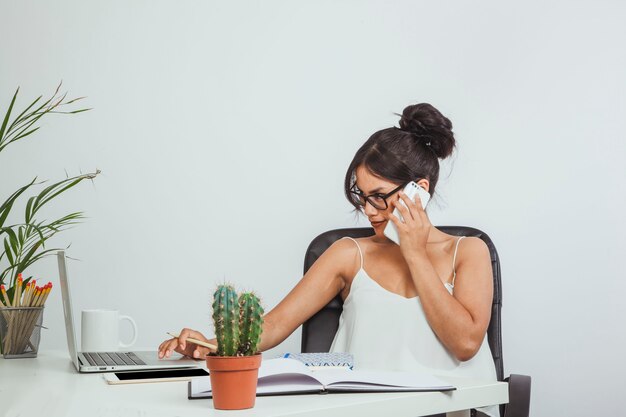 Mujer de negocios hablando por teléfono y trabajando con el portátil