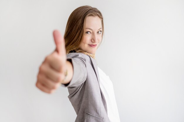 Mujer de negocios hermosa confiada que muestra el pulgar para arriba