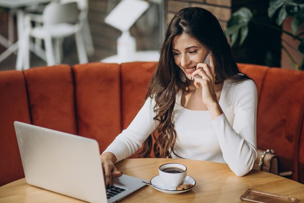 Mujer de negocios hermosa joven trabajando en equipo en un café