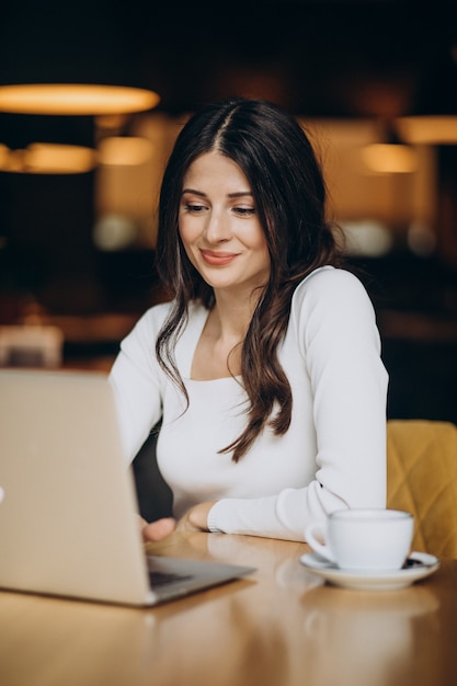 Mujer de negocios hermosa joven trabajando en equipo en un café