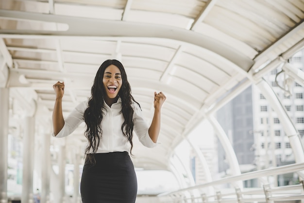 Foto gratuita la mujer de negocios joven alcanza la meta, levantó las manos.