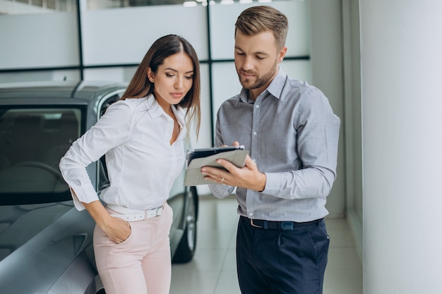 Mujer de negocios joven comprando un coche en la sala de exposición de coches