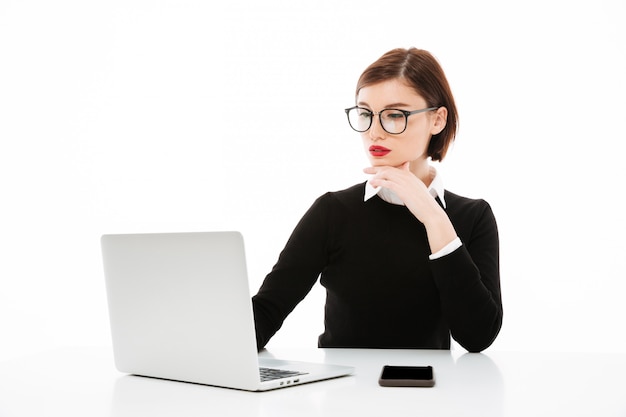 Mujer de negocios joven concentrada usando la computadora portátil.