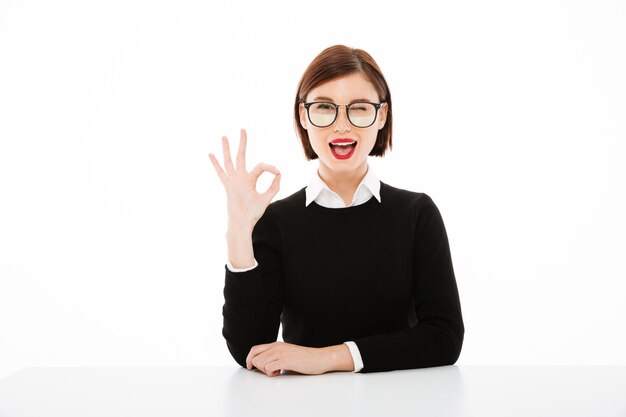 Mujer de negocios joven feliz con gafas mostrando gesto bien.