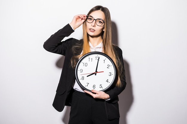 Mujer de negocios joven hermosa que sostiene en las manos el reloj en blanco