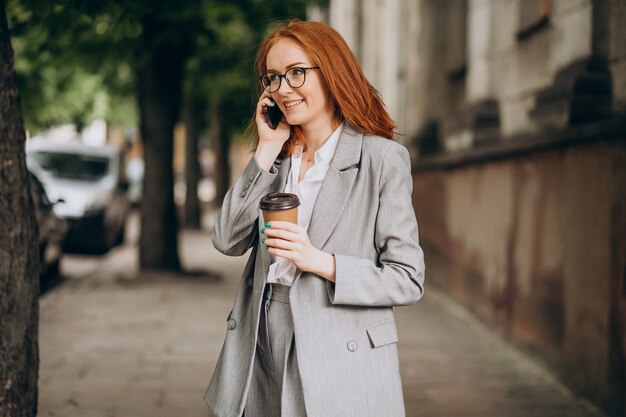 Mujer de negocios joven con pelo rojo con teléfono