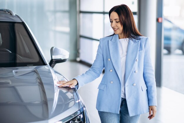 Mujer de negocios joven que elige un coche en un salón de autos