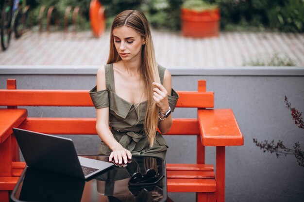 Mujer de negocios joven que trabaja en la computadora portátil afuera en un café