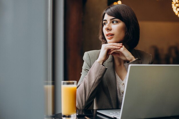 Mujer de negocios joven que trabaja en la computadora portátil en un café