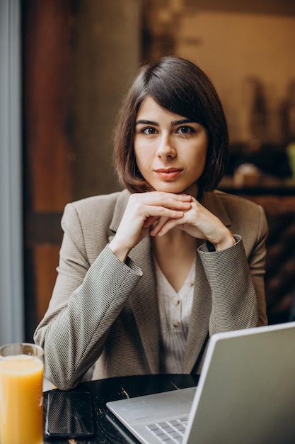 Mujer de negocios joven que trabaja en la computadora portátil en un café