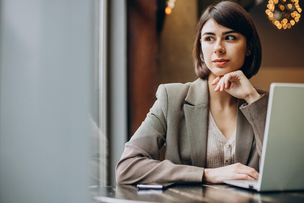 Mujer de negocios joven que trabaja en la computadora portátil en un café