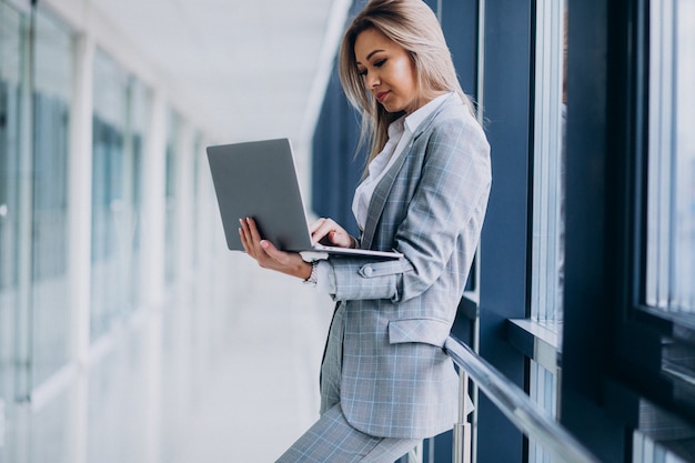 Mujer de negocios joven que trabaja en la computadora portátil en una computadora