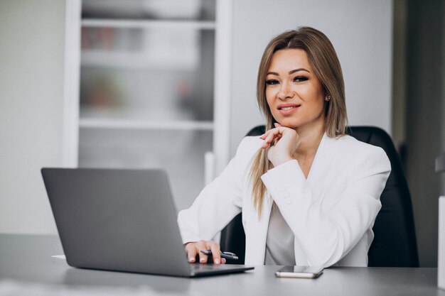 Mujer de negocios joven que trabaja en la computadora portátil en una oficina