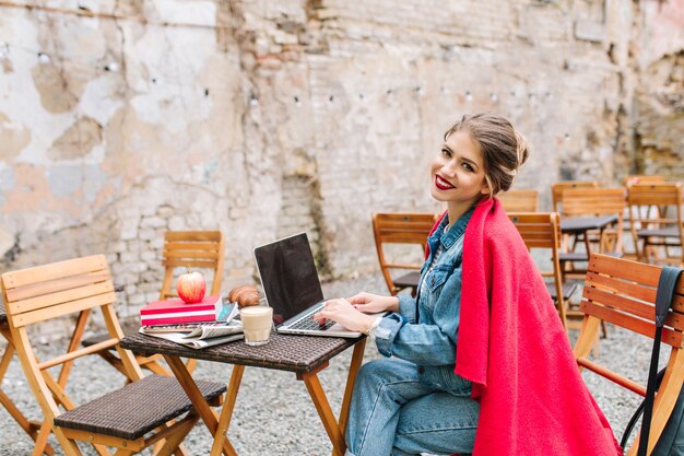 Mujer de negocios joven que trabaja en el nuevo proyecto usando la computadora portátil durante la hora del almuerzo en el café al aire libre.