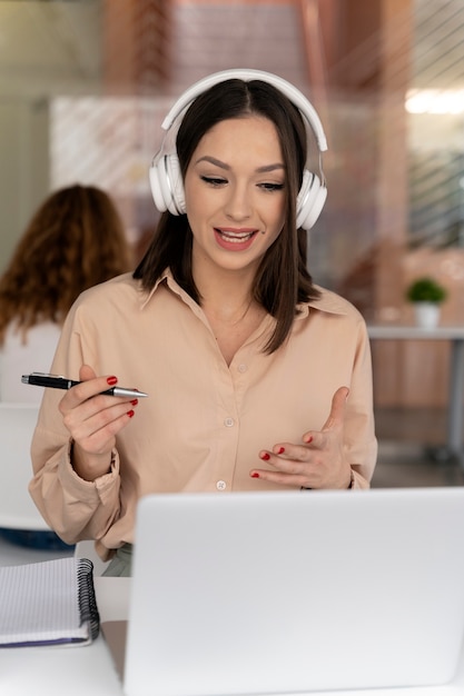 Mujer de negocios joven que trabaja en la oficina con ordenador portátil y auriculares