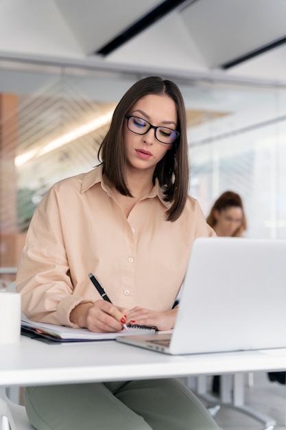 Mujer de negocios joven que trabaja en su escritorio con ordenador portátil