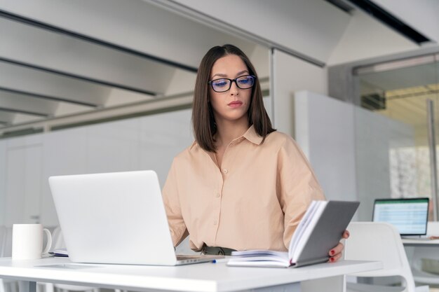 Mujer de negocios joven que trabaja en su escritorio con ordenador portátil