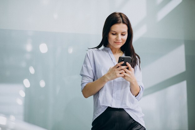 Mujer de negocios joven que usa el teléfono en la oficina