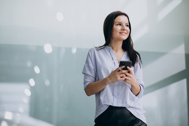 Mujer de negocios joven que usa el teléfono en la oficina