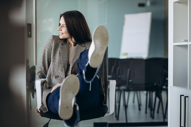 Foto gratuita mujer de negocios joven sentada en una silla en una oficina