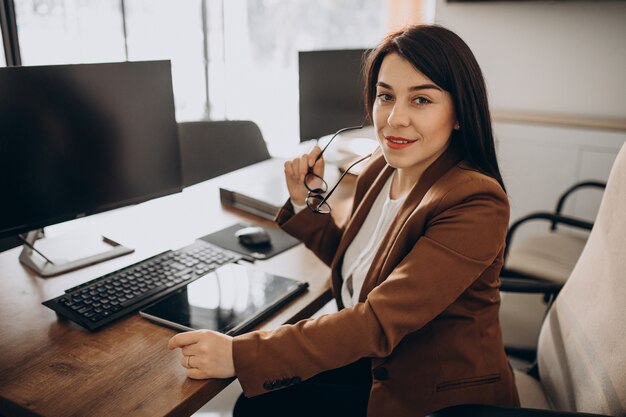 Mujer de negocios joven sentado en el escritorio y trabajando en equipo