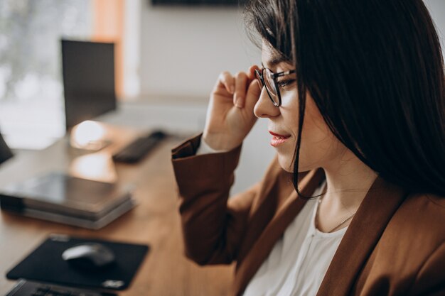 Mujer de negocios joven sentado en el escritorio y trabajando en equipo