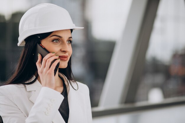 Mujer de negocios joven con sombrero duro en el objeto de construcción