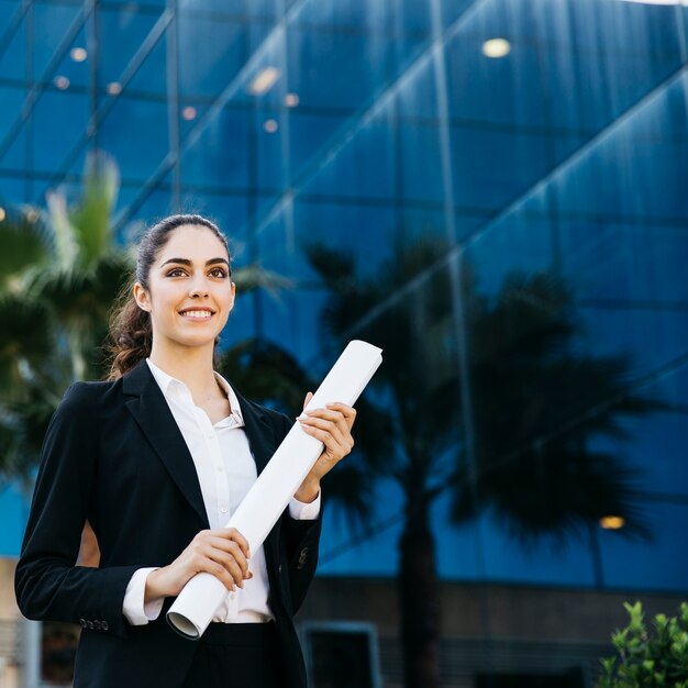 Foto gratuita mujer de negocios joven sujetando plano