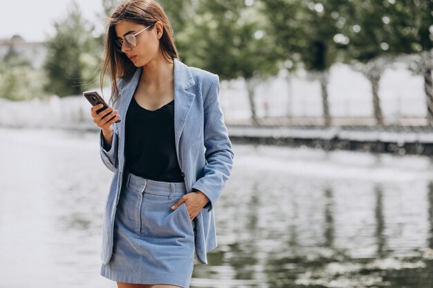 Mujer de negocios joven con teléfono en el parque