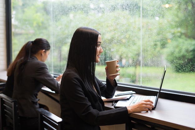 Mujer de negocios joven tener un descanso con un café mientras se trabaja en la computadora portátil en la oficina